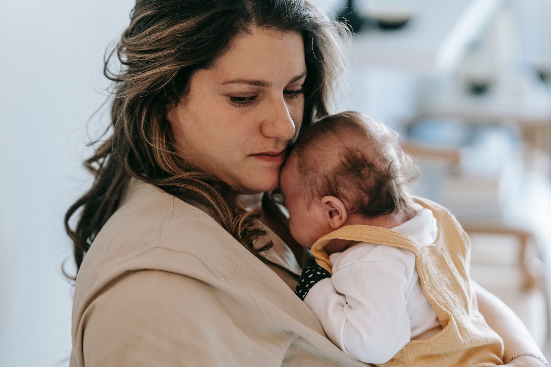 Mãe segurando bebê dormindo no colo, guia de como fazer o bebê dormir com segurança por idade