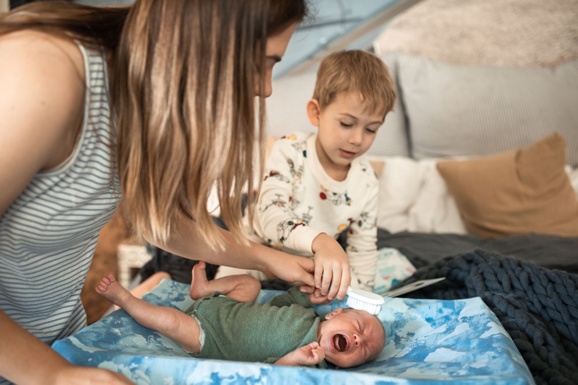 Mãe escovando suavemente o couro cabeludo do bebê com crosta lactea após o banho
