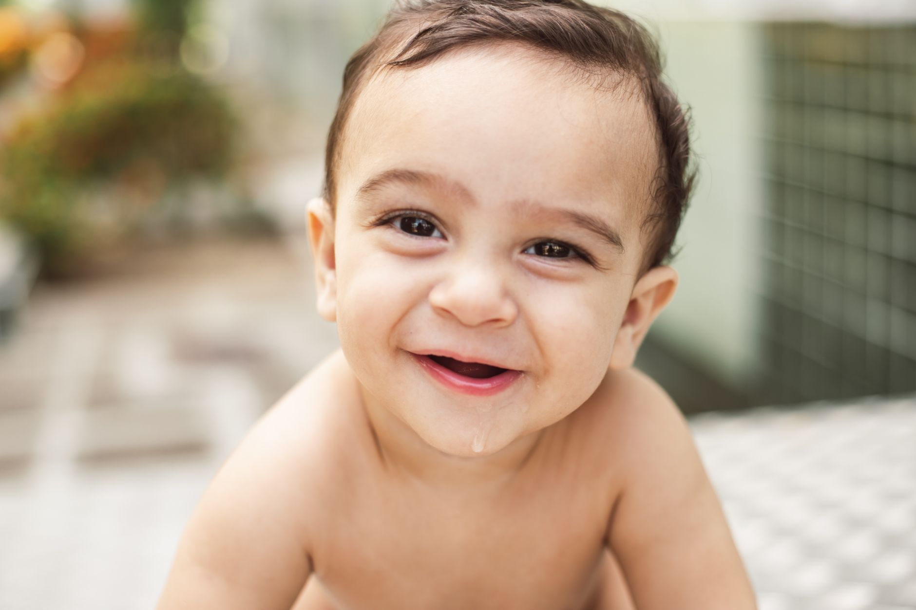 Mãe segura o bebê próximo à janela com luz suave, tema vitamina D no bebe